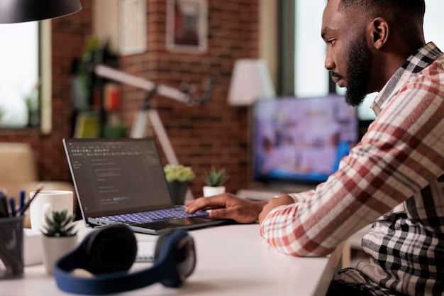 A man sits at a laptop and writes program code